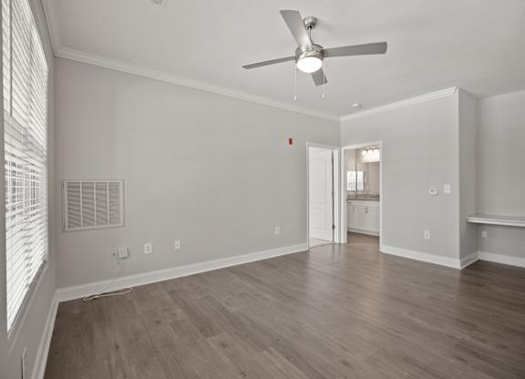 A room with a ceiling fan and wooden flooring.