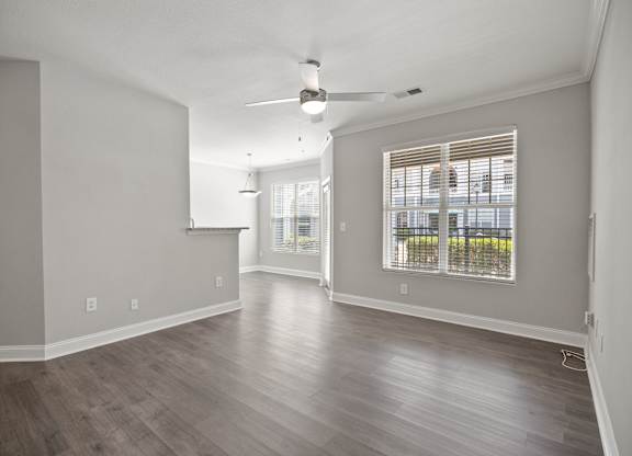 A room with a ceiling fan and a window with blinds.