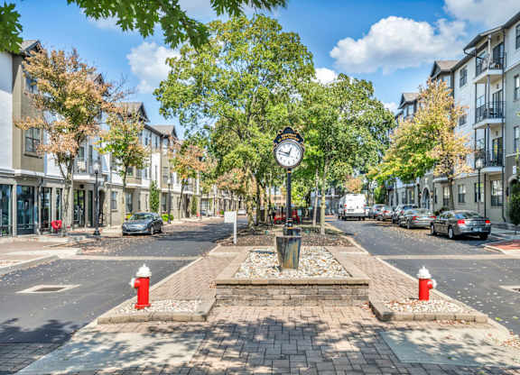 A clock at a crosswalk in a city street.