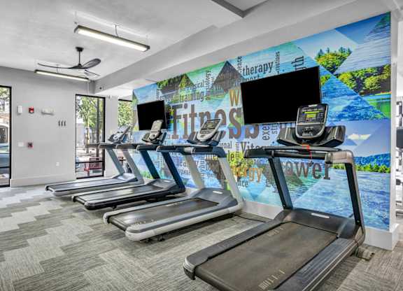 A gym with treadmills and a wall mural.