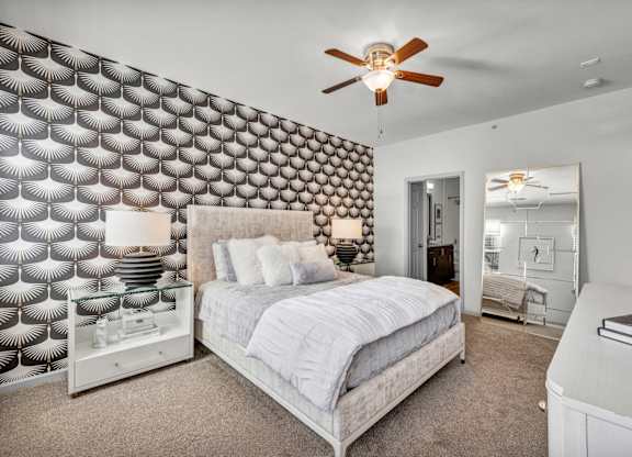 A bedroom with a bed, dresser, and a ceiling fan.