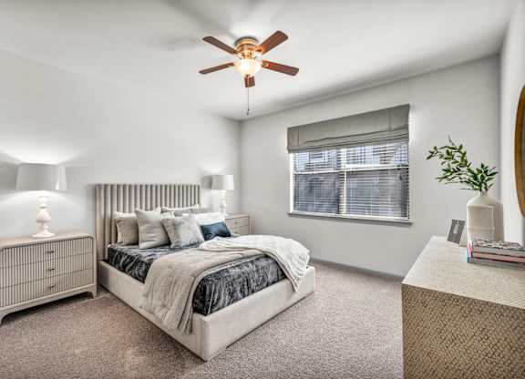 A bedroom with a bed, nightstand, and window.