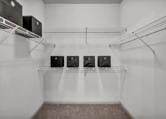 A room with a white wall and a shelf with four speakers on it.