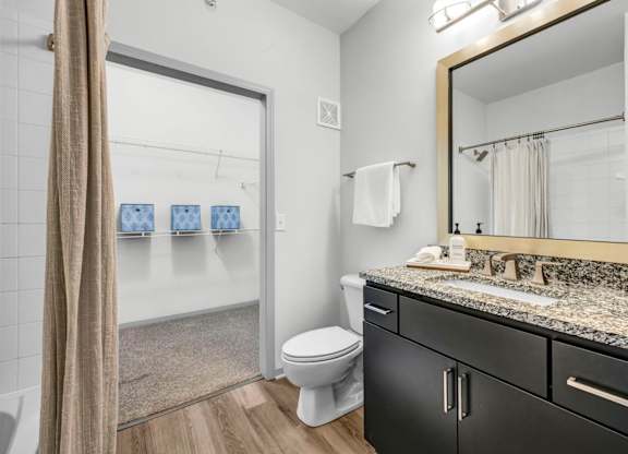 A bathroom with a toilet, sink, and mirror.