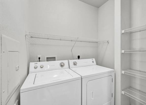 Two white front loading washing machines in a laundry room.