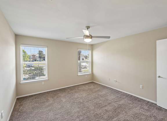 A room with a ceiling fan and carpeted floor.
