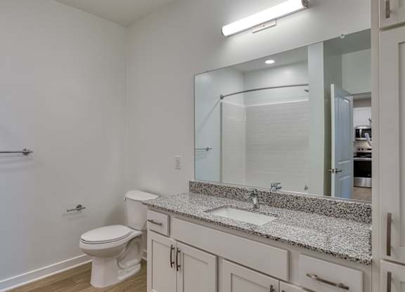 A white bathroom with a toilet, sink, and mirror.