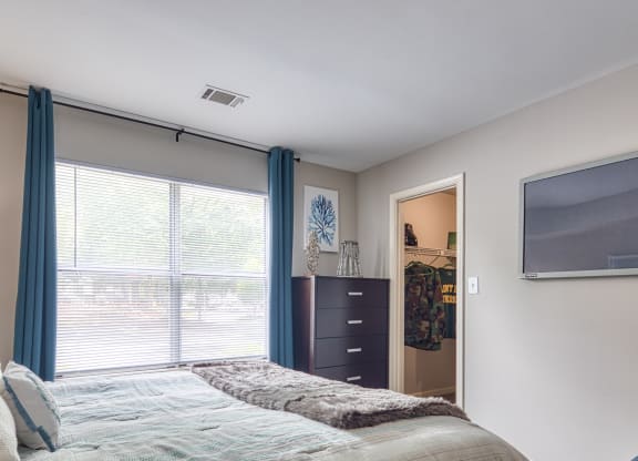 a bedroom with a large window and a bed with blue curtains