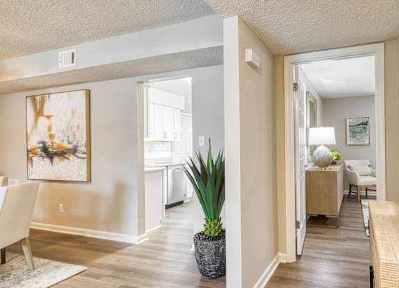 A living room with a painting on the wall and a potted plant on the floor.