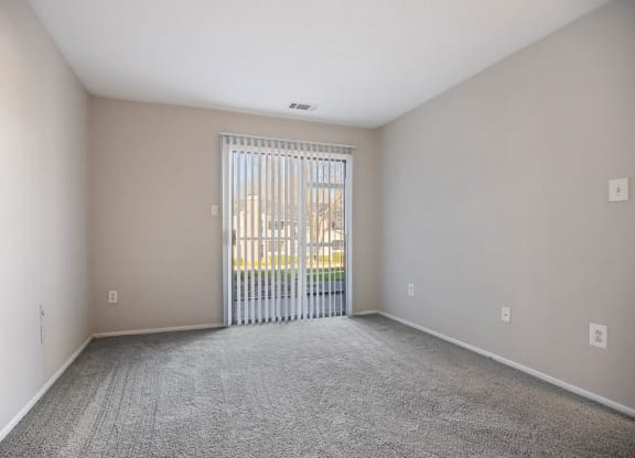 a spacious living room with a sliding glass door to a balcony
