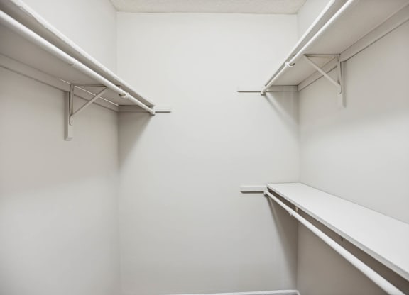 a walk in closet with white walls and a shelf