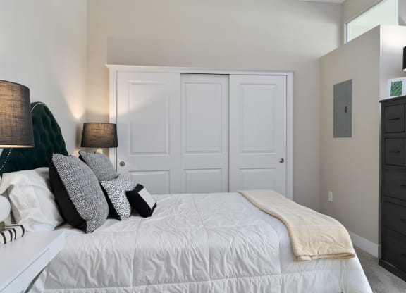 a bedroom with a white bed and white closet doors at Hayden Lofts, Dublin, OH