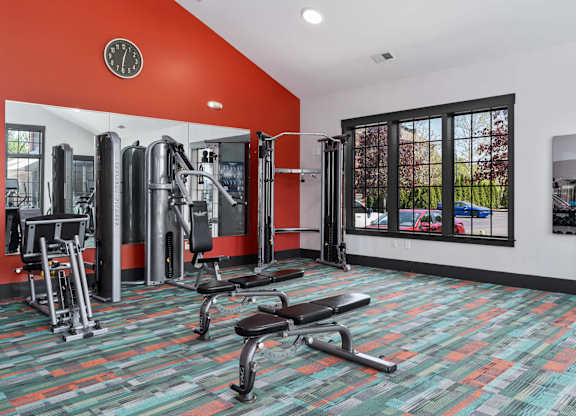A gym with a variety of equipment including a bench, weights, and a mirror.