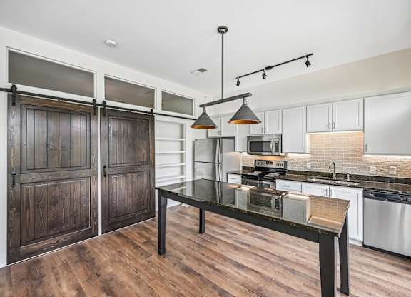 A modern kitchen with a dark wood floor and white walls.