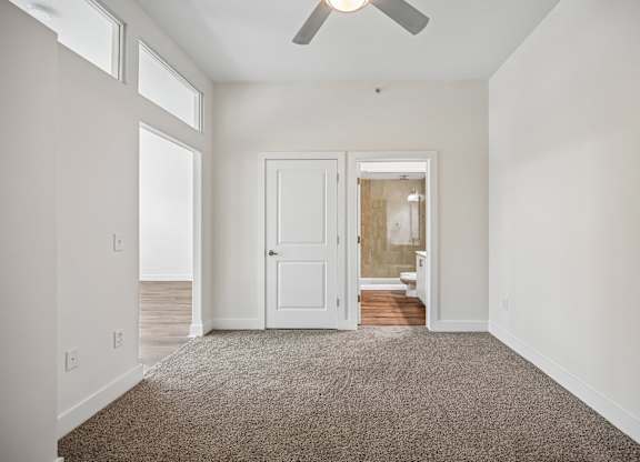 A room with a carpeted floor and a ceiling fan.