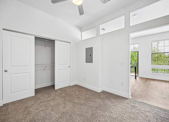 A spacious room with a ceiling fan and a door leading to a balcony.
