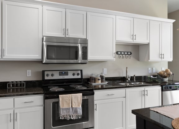 a white kitchen with stainless steel appliances and white cabinets at Hayden Lofts, Dublin, Ohio
