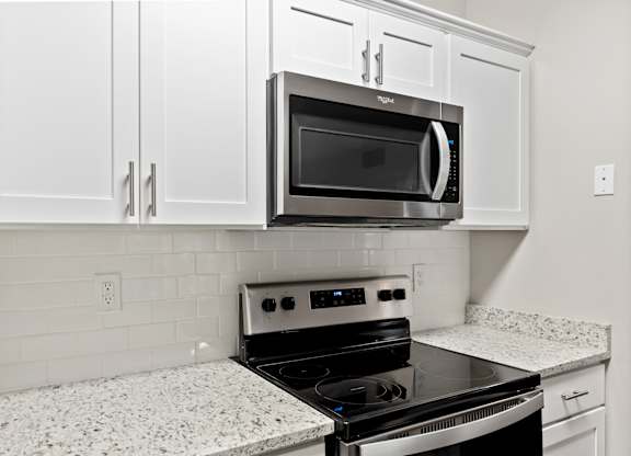 A kitchen with a black microwave oven mounted above a stove.