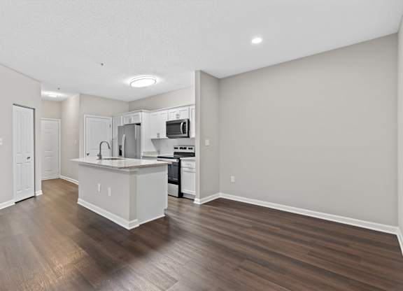 A kitchen with a white countertop and wooden floors.