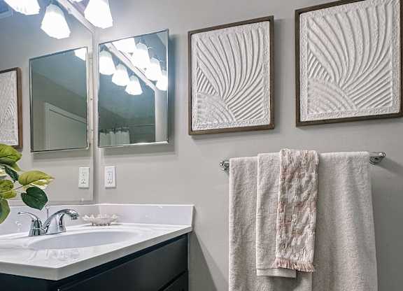 A bathroom with a white sink and a towel hanging on the wall.