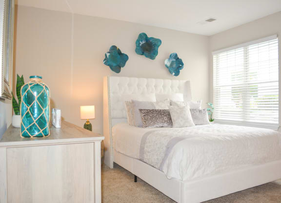a bedroom with a white bed and blue flowers on the wall