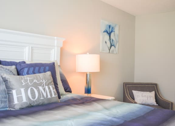 a bedroom with a bed with blue pillows and a lamp