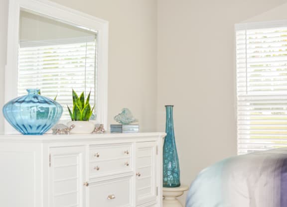 a white dresser with a mirror and blue vases on it