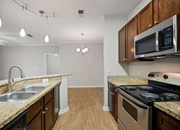 A kitchen with a stove, sink, and microwave.