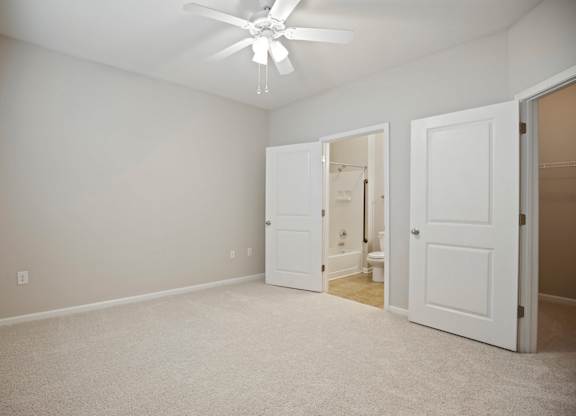 A room with a ceiling fan and three doors.