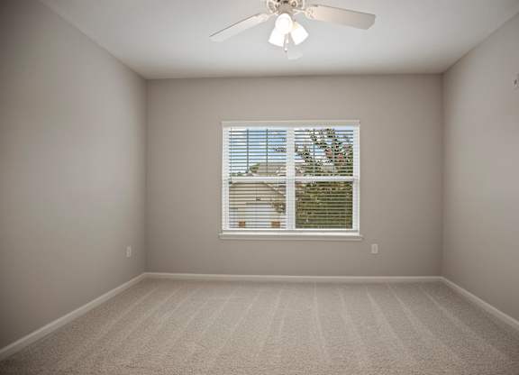 A room with a ceiling fan and a window with blinds.