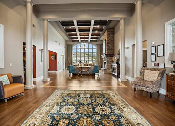 A large, open living room with a rug on the floor and a staircase in the background.