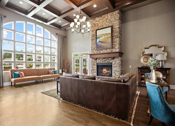 A living room with a brown leather couch and a stone fireplace.