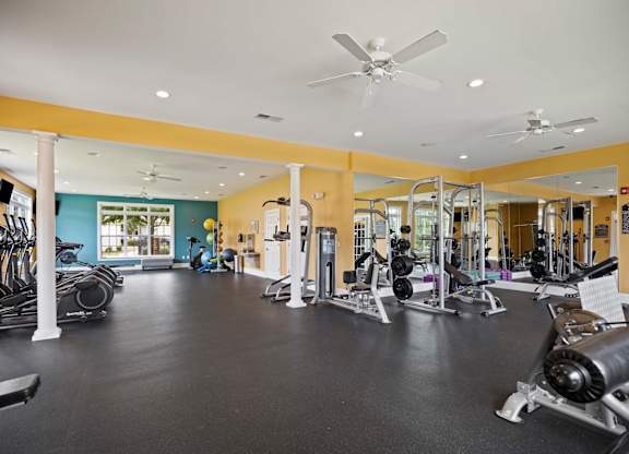 A gym with a variety of equipment including treadmills, weights, and exercise machines.