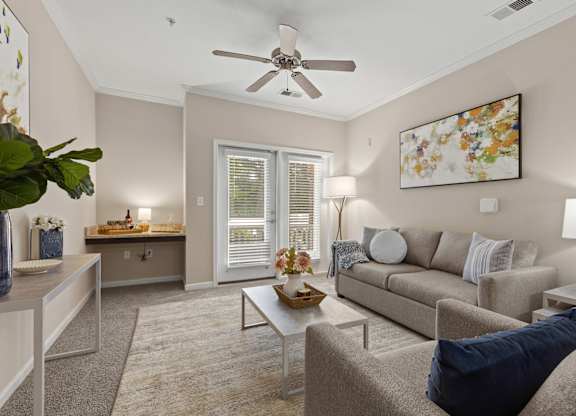A living room with a beige couch, a coffee table, and a ceiling fan.