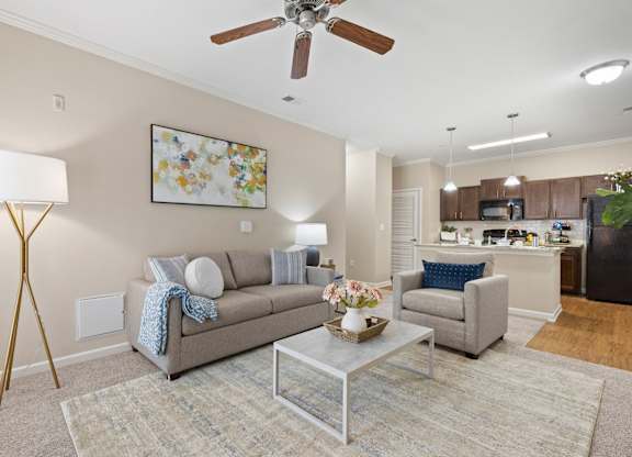 A living room with a grey couch, a coffee table, and a ceiling fan.