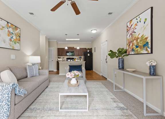 A living room with a grey couch and a glass coffee table.