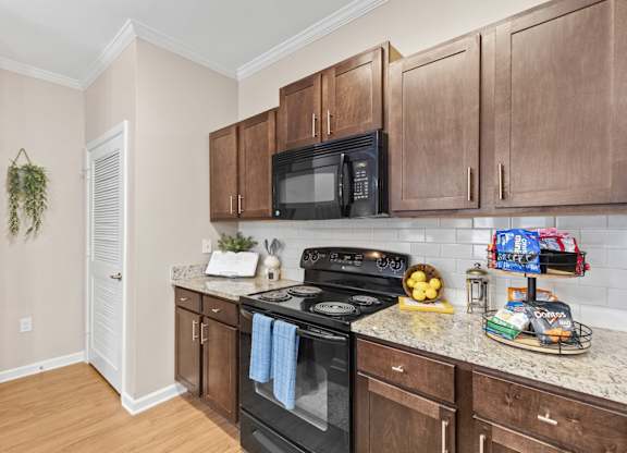 A kitchen with a black microwave, black oven, and wooden cabinets.