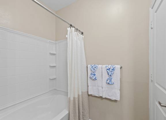 A white bathroom with a white tub and a white shower curtain.