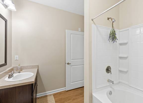 A white bathtub with a shower head and a white door.