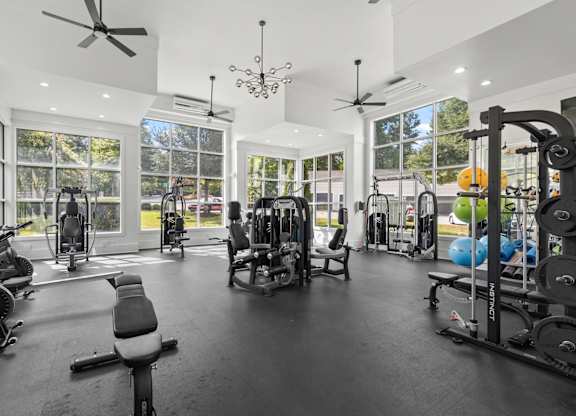 A spacious gym with a variety of equipment and a person working out.