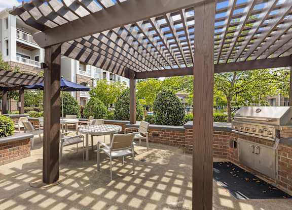 A patio with a table and chairs under a wooden pergola.