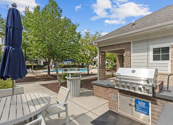 A blue umbrella is on a table next to a grill.