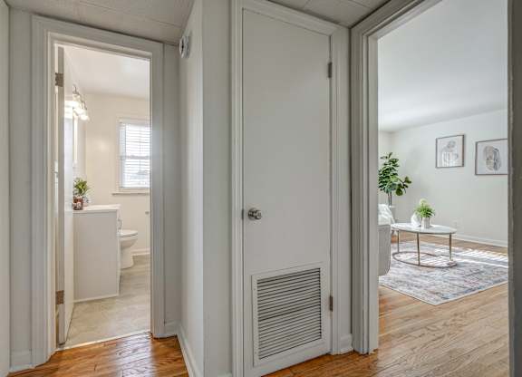 A white door is open to a room with a table and a potted plant.