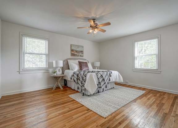 A bedroom with a bed, a fan, and a rug.