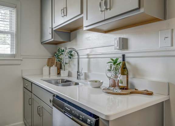 A kitchen with a white countertop and a stainless steel dishwasher.