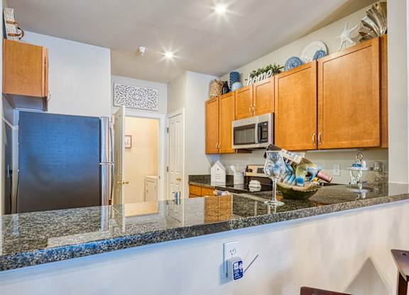 A kitchen with a granite counter top and wooden cabinets.