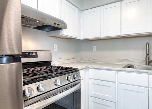 A modern kitchen with a stainless steel stove and white cabinets.