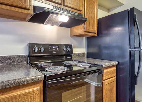 A kitchen with a black stove top oven and a black refrigerator.