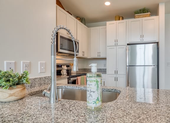 a kitchen with granite counter tops and a stainless steel refrigerator at Allure at Edinburgh, Virginia