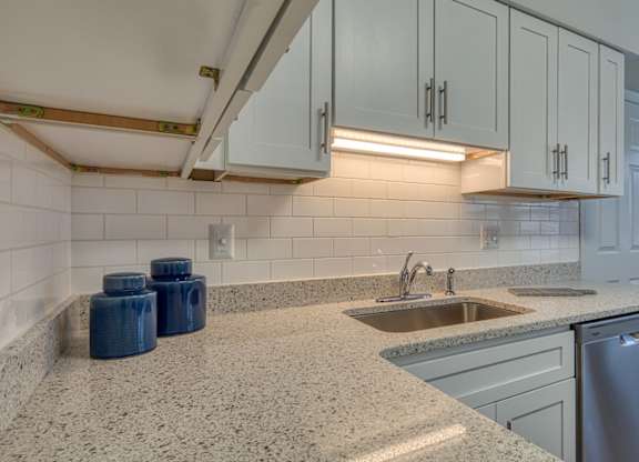 A kitchen with a granite countertop and a stainless steel dishwasher.